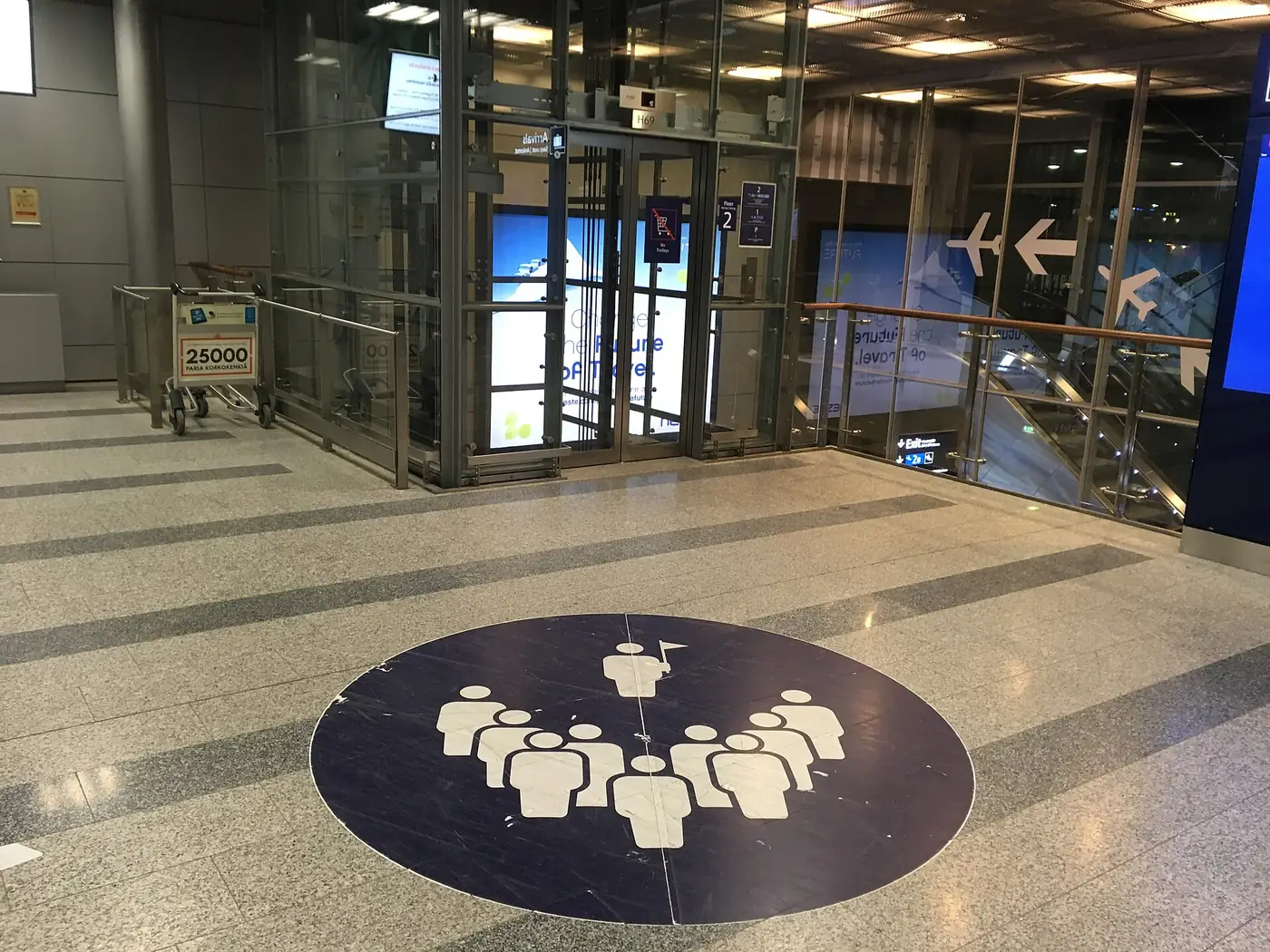 A circular meeting-point symbol on the floor inside Helsinki Airport