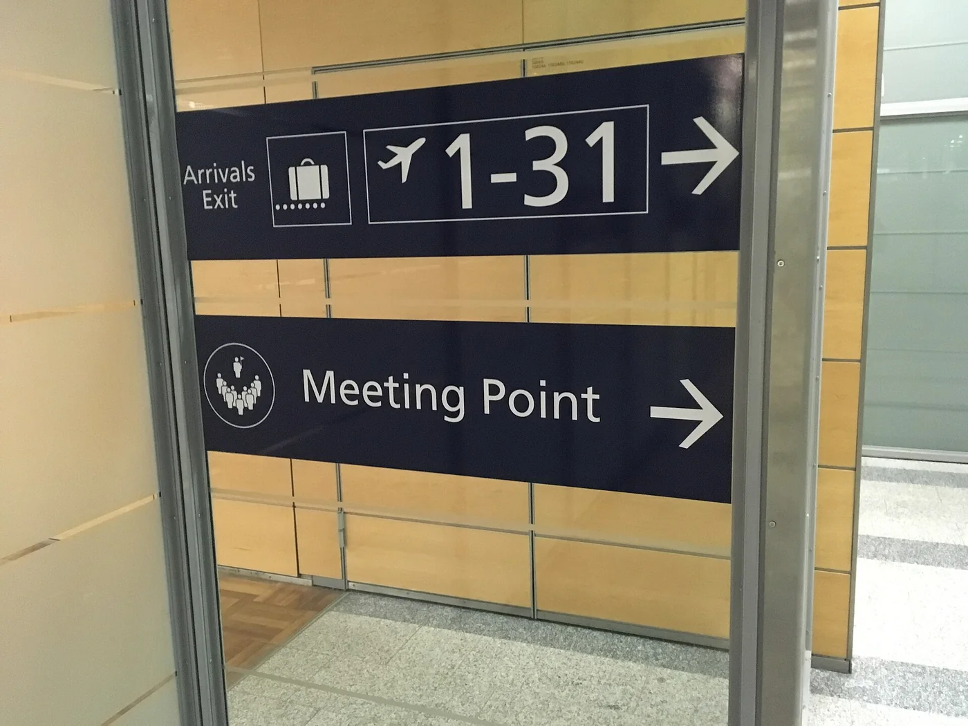 A Helsinki Airport sign pointing to a meeting point and to arrivals